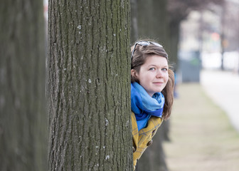 Young woman behind tree