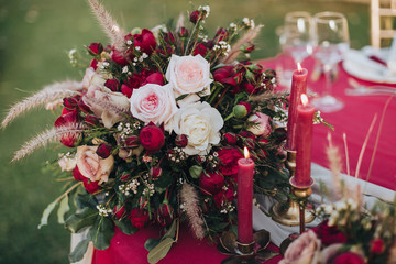 Wedding. Banquet. Grain. Artwork. At the banquet table with tablecloth colors Marsala, is the composition of flowers and greenery, cutlery and candles