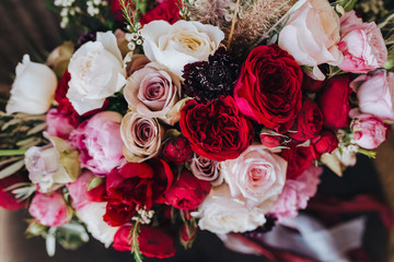 Wedding. Boutonniere. Grain. Artwork. A bouquet of red flowers, pink flowers and greenery with silk ribbons is in the black chair