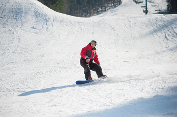 Snowboarder rides over fresh snow after jumping on the slope in winter, extreme sport