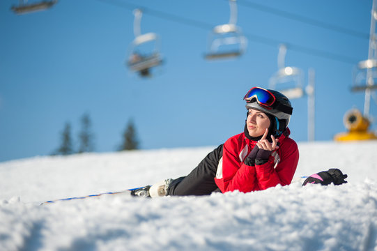 Female skier with skis on snowy at mountain top in sunny day,  ski lifts and blue sky in background. Close-up