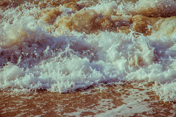 Soft foam wave of sea on sandy beach close up