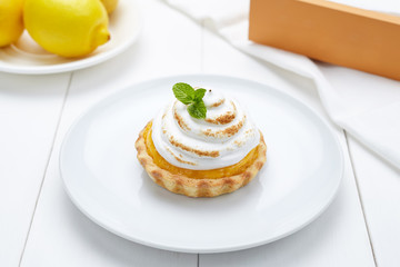 Lemon tart with whipped cream and mint sweet dessert on white plate