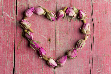 Rose flowers in heart shape on old wooden background