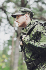 young soldier with backpack in forest