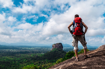 Hiker with backpack enjoying views  from top of a mountain. Sigiriya Rock, Pidurangala Rock, Sri Lanka.