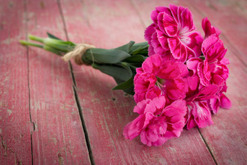 Bouquet of purple carnations on pink wooden background