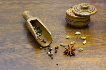 star anise cardamom on the table, pepper in a wooden spoon and