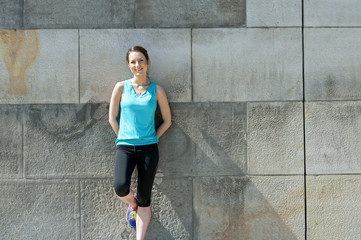 Woman resting after run by the wall urban.
