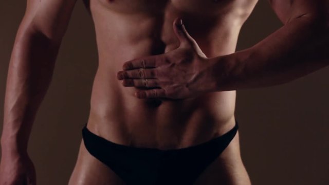 Brutal guy showing his muscles. Touching abs. Graded