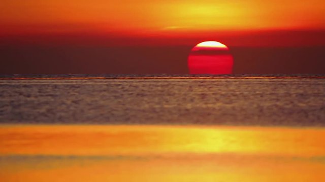 The sun setting behind the sea. Amazing sunset at the beach.