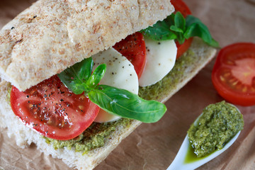 Closeup of a fresh sandwich with mozzarella, tomatoes, pesto and