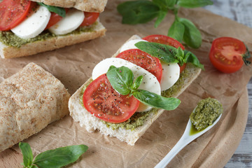Closeup of a fresh sandwich with mozzarella, tomatoes, pesto and