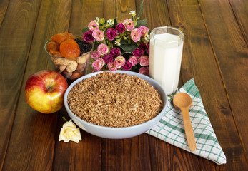 Bowl buckwheat cereal,  glass  milk,  apple, nuts  on dark wood.