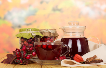 Rowan berries, rose hips, drink  cup tea on  autumn leaves.