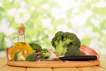 Fresh broccoli,  bottle  oil, spices, knife , towel on abstract green .