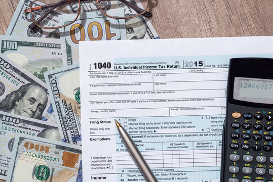 federal income tax return 1040 documents with pen, calculator, dollars