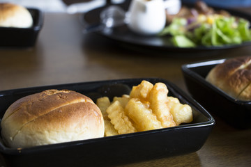 Bun served with fries in plain black ceramic container