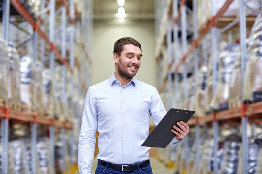 happy businessman with clipboard at warehouse
