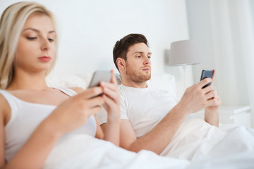 couple with smartphones in bed
