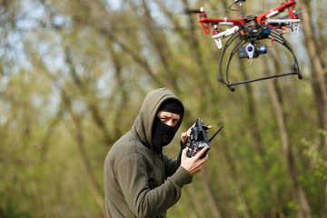 Man in mask operating a drone with remote control.