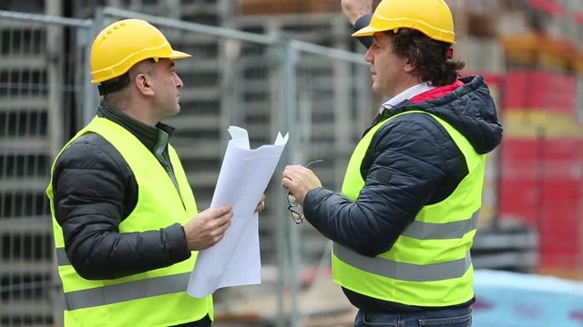 Engineers with blueprints checking building site construction