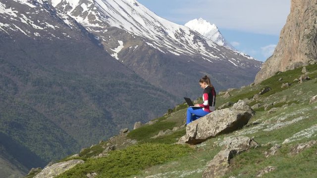 Woman with laptop on the background of snowy peak