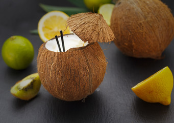 Coconut cocktail on a black table with lemon and kiwi.