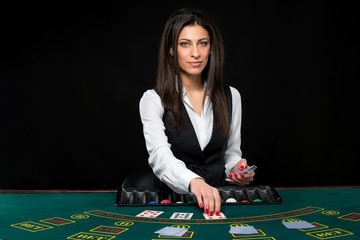 The beautiful girl, dealer, behind a table for poker