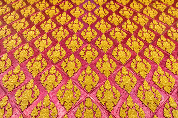 Perspective religion art of Thai Buddhism on Temple wall. The design is yellow or golden floral pattern with red background.