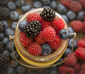 different berries in a basket on a wooden table
