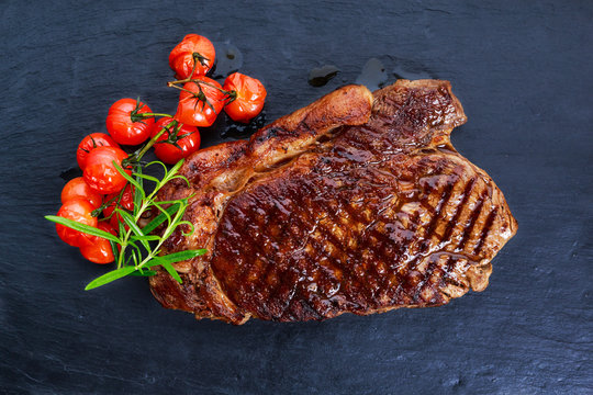Grilled Beef Sirloin Steak on blue stone background, with vegetables.