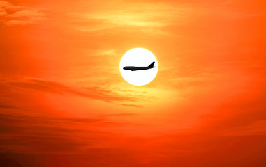 Closeup of the airplane silhouette on the beautiful sun and red sky.