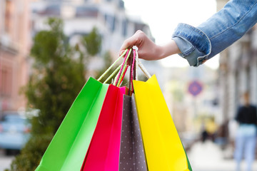 closeup picture of multi colored shopping bags with a hand