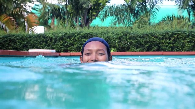 Woman swims in the pool. Cheerful girl in a bathing cap swims in the swimming pool.