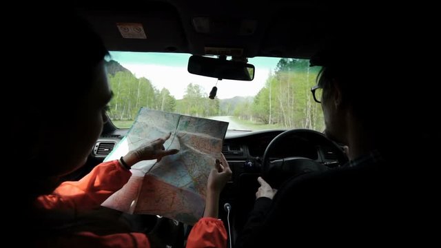 slowmotion. Rear view shot of a young couple on road trip reading a map