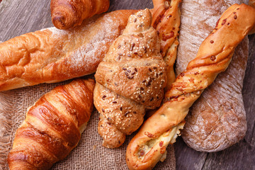 Assortment of fresh baked bread and croissants on burlap on rustic table