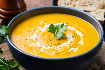 Pumpkin and carrot soup with cream and parsley