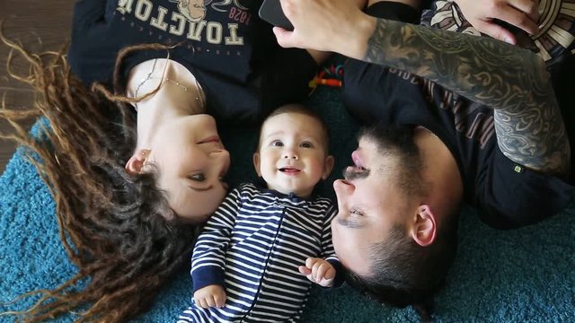 Happy Young Family Lying On The Floor, Laughing