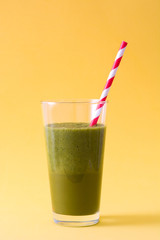 Healthy drink with spinach, cucumber, apple, lime and ginger on yellow background
