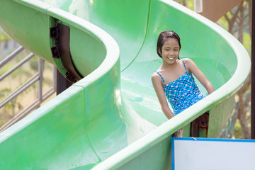 Asian girl have fun to playing a slide in the water park.