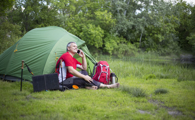 The man sitting next to mobile phone charges from the sun.