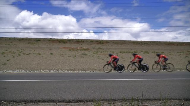 Team of Professional cyclists riding together in a pack, super slow motion. Location Folsom California, no identifiable logos or faces. 