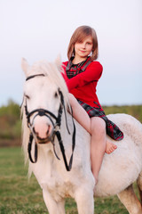 Portrait of a baby girl sitting on a white pony