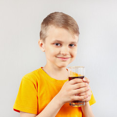 Little blonde boy with a glass of fresh cola