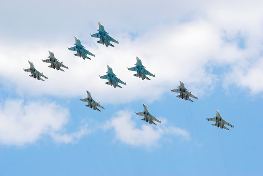 Группа из многофункциональных истребителей-бомбардировщиков Су-34, многоцелевых всепогодных истребителей Су-27 и многоцелевых сверхманёвренных истребителей Су-35с в небе