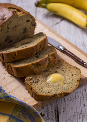 Sliced Banana Bread on Cutting Board with Bananas in the Background