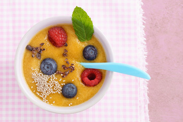 Peach smoothie bowl with blueberries, raspberries, white chia seeds and cocoa nibs