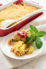Homemade strawberry crumble on white wooden background