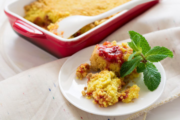 Homemade strawberry crumble on white wooden background